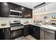 Modern kitchen showcasing dark cabinets, stainless steel appliances, and white backsplash, complemented by stylish pendant lighting at 6775 Newland St, Arvada, CO 80003