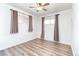 Minimalist bedroom with laminate floors and two windows with beige blackout curtains at 9100 Yucca Way, Thornton, CO 80229
