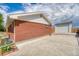 Brick home exterior, large concrete driveway, and detached garage, highlighting outdoor space at 9100 Yucca Way, Thornton, CO 80229