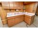 Vintage basement kitchen featuring wood cabinets, pink laminate countertops, and paneling at 9100 Yucca Way, Thornton, CO 80229