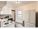 Well-lit kitchen with white appliances, tile floors, and a view into the next room at 827 S Sherman St, Denver, CO 80209