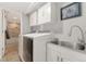 Functional laundry room with modern washer and dryer, utility sink, and convenient access to bathroom at 7391 S Marion St, Centennial, CO 80122