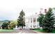 Stately white manor with grand columns, an American flag, and landscaped grounds exudes elegance and charm at 11404 W Sharkstooth Peak, Littleton, CO 80127