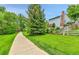 Exterior shot of light blue house with large tree and sidewalk leading to yard at 11404 W Sharkstooth Peak, Littleton, CO 80127