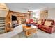 Spacious living room with brick fireplace, red couches, and stairs to upper floor at 11404 W Sharkstooth Peak, Littleton, CO 80127