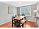 Sunny dining room features hardwood floors, a wooden table and bench, and a large window at 13935 E Idaho Pl, Aurora, CO 80012