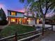 Charming two-story home with a well-manicured lawn, brick accents, and a three-car garage at dusk at 13935 E Idaho Pl, Aurora, CO 80012
