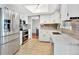 Bright kitchen featuring stainless steel appliances, white cabinetry, and tile backsplash at 13935 E Idaho Pl, Aurora, CO 80012