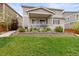 Backyard with covered porch, outdoor grill, and landscaped retaining wall and garden at 3319 Starry Night Loop, Castle Rock, CO 80109
