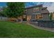 Twilight view of the backyard with stone pavers, outdoor kitchen, hot tub, and well-manicured lawn at 3540 Brushwood Dr, Castle Rock, CO 80109