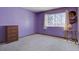 Bright bedroom features a large window, neutral carpeting and warm lavender painted walls at 11810 Mesa View Rd, Larkspur, CO 80118