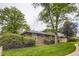 Exterior view of a well-maintained townhouse with mature trees and shrubs surrounding the property at 8759 E Roundtree Ave, Greenwood Village, CO 80111