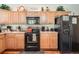 Functional kitchen with oak cabinets, black appliances, and a view of dining area in the background at 552 S Mobile Pl, Aurora, CO 80017