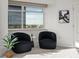 A sitting area with large windows showcasing a city view, two stylish chairs and modern decor at 1891 Curtis St # 1820, Denver, CO 80202