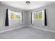 Cozy bedroom featuring new carpet, neutral decor, two bright windows, and ample natural light at 721 Forest View Rd, Monument, CO 80132