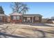 Charming brick home featuring a large driveway and classic design elements under a clear blue sky at 7070 W 39Th Ave, Wheat Ridge, CO 80033