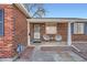 Close up of the front of a red brick home with seating, a storm door, and brick landscaping at 7070 W 39Th Ave, Wheat Ridge, CO 80033