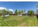 A lush green backyard features mature trees, a fence and blue skies overhead at 8800 W Kentucky Ave, Lakewood, CO 80226