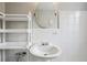 Bright bathroom with white tile, pedestal sink, decorative shelving, and oval mirror at 1130 N Pennsylvania St # 208, Denver, CO 80203