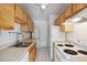 Efficient kitchen design with wooden cabinets and white appliances, including in-unit washer and dryer at 1130 N Pennsylvania St # 208, Denver, CO 80203
