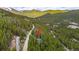 A captivating aerial shot showcases property with tall pine trees. A red arrow points to the subject property at 542 Harris Dr, Idaho Springs, CO 80452