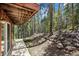 Stone accented backyard featuring sliding glass doors and views of the tall pine trees at 542 Harris Dr, Idaho Springs, CO 80452