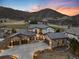 Stunning home exterior with stone accents, tile roof, three-car garage, and beautiful mountain views at sunset at 8033 Galileo Way, Littleton, CO 80125