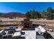 Comfortable outdoor patio with cozy seating around a stone fireplace and scenic mountain views at 8033 Galileo Way, Littleton, CO 80125