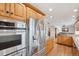 A well-lit kitchen features stainless steel appliances, wood cabinets, granite counters and wood floors at 2287 Pinto Trl, Elizabeth, CO 80107