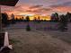 A stunning view of sunrise over the treeline and fenced in yard, viewed from the house at 2287 Pinto Trl, Elizabeth, CO 80107