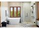 Modern bathroom featuring a soaking tub under a wood-framed window and a glass-enclosed shower with marble tile at 3720 Ranch Hand Ln, Castle Rock, CO 80104
