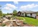 Beautiful property features a stone firepit, lush garden, flowing water feature and elegant home with tile roof at 3720 Ranch Hand Ln, Castle Rock, CO 80104