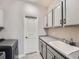 Well-lit laundry room with utility sink and cabinets, plus a front-load washer at 23709 E Caleb Pl, Aurora, CO 80016