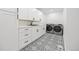 Well-organized laundry room with patterned floors, white cabinets, and modern washer and dryer at 49 Charlou Cir, Cherry Hills Village, CO 80111