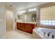 Well-lit bathroom featuring a dual sink vanity, soaking tub, and neutral tile flooring at 973 Orion Way, Castle Rock, CO 80108