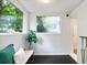 Bright sunroom with a white bench, dark floors and large windows providing ample natural light and backyard views at 3613 Julian St, Denver, CO 80211