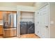 Laundry area with modern washer and dryer, adjacent to a refrigerator in a well-lit space at 10507 W Maplewood Dr # E, Littleton, CO 80127