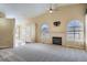 Spacious living room featuring a cozy fireplace, ceiling fan and soft, neutral carpet at 10507 W Maplewood Dr # E, Littleton, CO 80127