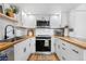 Modern kitchen with white cabinets, butcher block countertops, and stainless-steel appliances at 12478 W Nevada Pl # 208, Lakewood, CO 80228