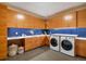 Laundry room with wood cabinets, blue tile, and washer/dryer at 825 Circle Dr, Boulder, CO 80302