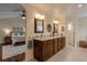 Bathroom with double vanity, granite countertop, wood cabinets, decorative mirrors, and adjacent bedroom at 3142 Captains Ln, Longmont, CO 80503