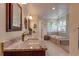 Bathroom with granite countertop, wood cabinets, decorative mirrors, a soaking tub, and a tiled glass-enclosed shower at 3142 Captains Ln, Longmont, CO 80503