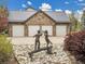 Stone-clad detached garage features a metal roof and three white doors, with a statue in the foreground at 1075 E Oxford Ln, Cherry Hills Village, CO 80113