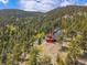 Mountain home surrounded by dense trees, situated on a hillside and exhibiting colorful modern design elements at 5896 Peregrine Trl, Golden, CO 80403