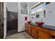 Chic bathroom featuring double vessel sinks, dark countertops, and a walk-in shower with decorative glass blocks at 5896 Peregrine Trl, Golden, CO 80403
