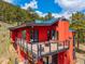 Exterior view of the red contemporary home featuring a fire pit, lounge seating, and mountain views at 5896 Peregrine Trl, Golden, CO 80403