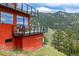 Exterior elevation of a modern red house featuring large windows and metal cable railings on the attached decks at 5896 Peregrine Trl, Golden, CO 80403