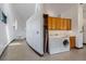 Bright laundry room featuring modern washer and dryer, with wood cabinets along curved hallway at 5896 Peregrine Trl, Golden, CO 80403
