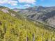 Scenic mountain view featuring lush forested hills, a distant red house, and winding roads under a blue sky at 5896 Peregrine Trl, Golden, CO 80403