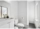 Modern bathroom with a white vanity, toilet, mirror, and window, creating a minimalist aesthetic at 1216 Perry St, Denver, CO 80204